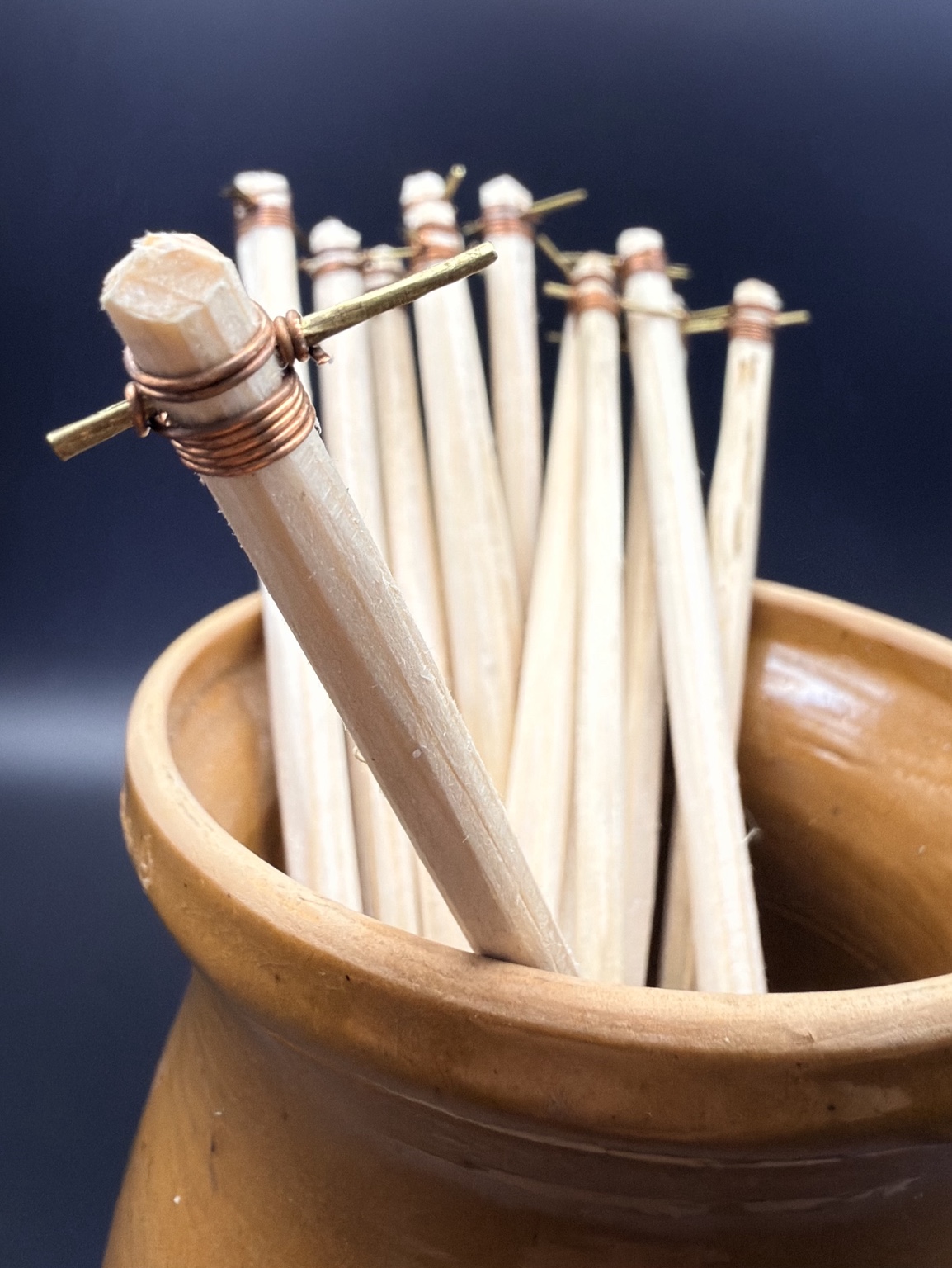 Traditional wax-writing tools (chișițe) with wooden handles and metal tips, standing in a clay pot