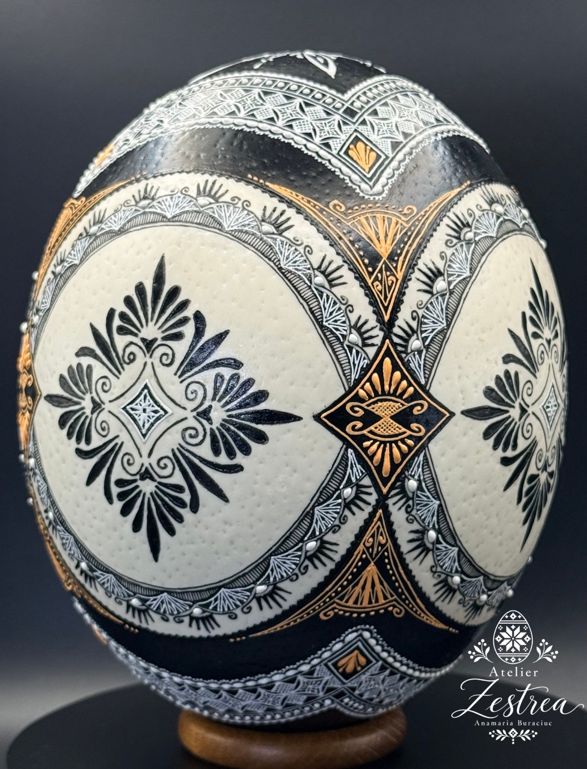 Ostrich egg with black floral medallions on ivory, framed by black-and-gold ornaments