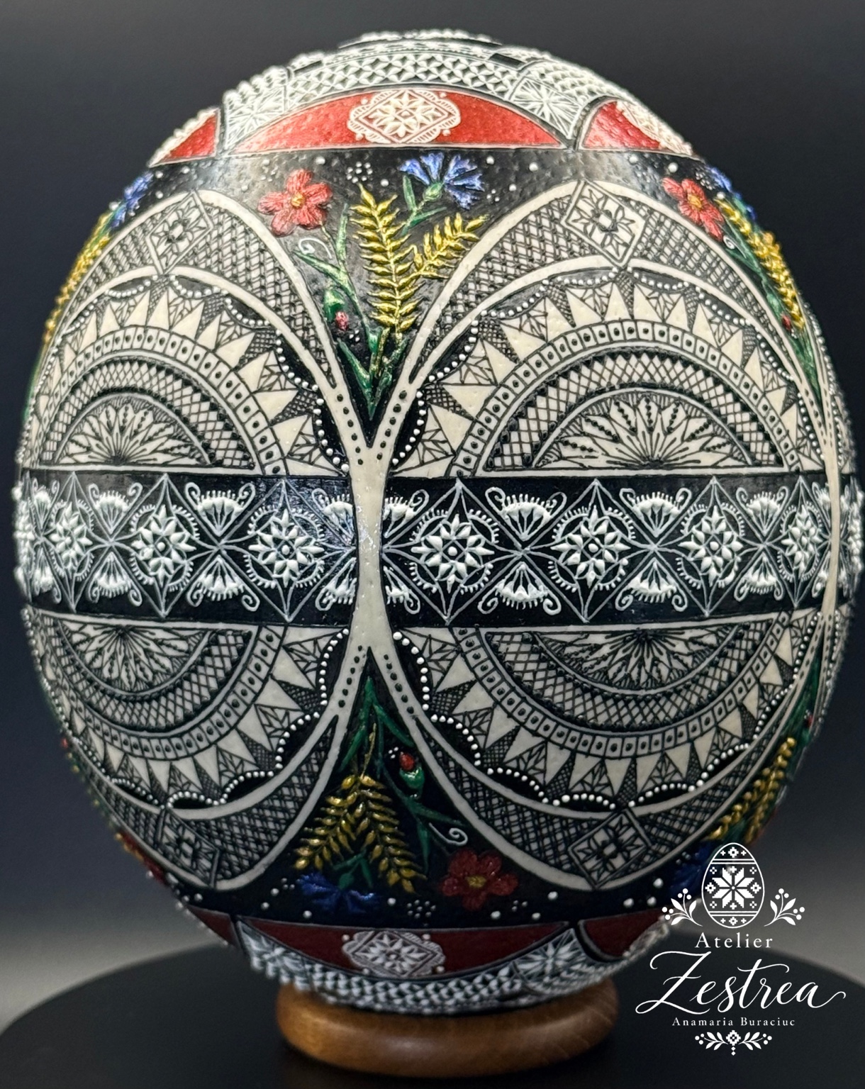 Dark ostrich egg with white geometric arches and colourful floral accents