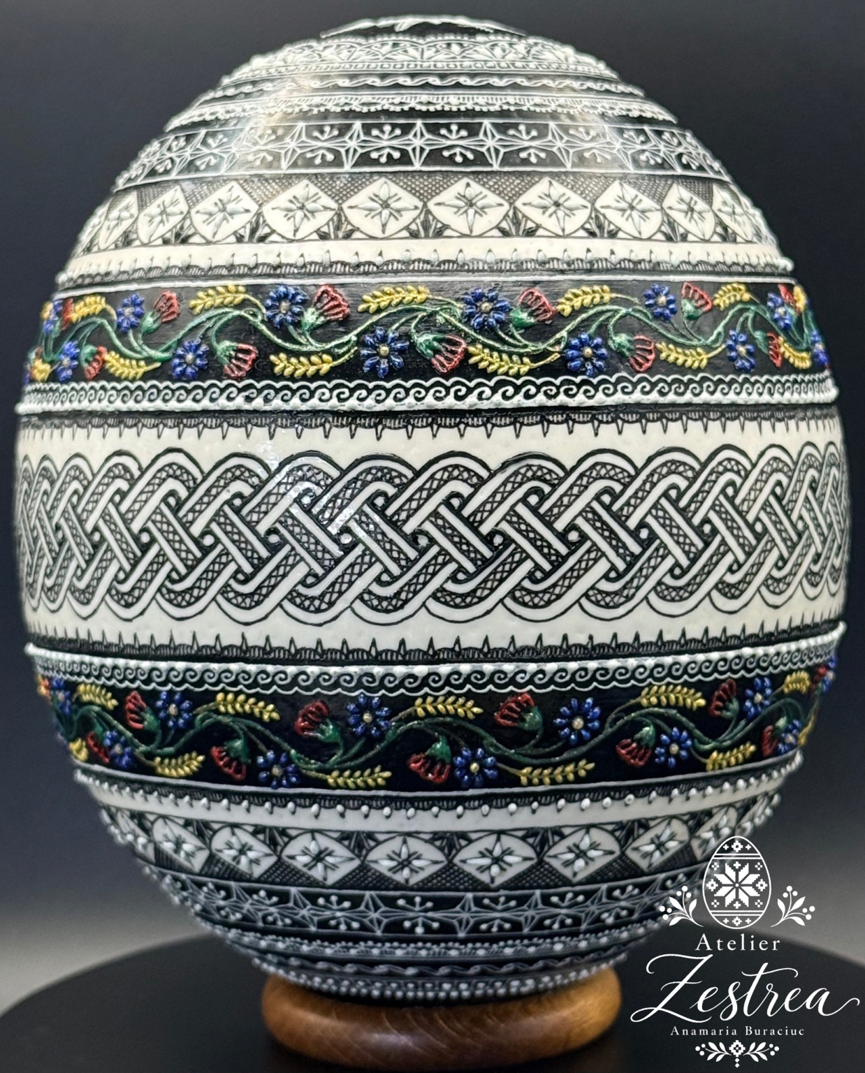 Ostrich egg with black-and-white interlaced bands and small colourful flowers
